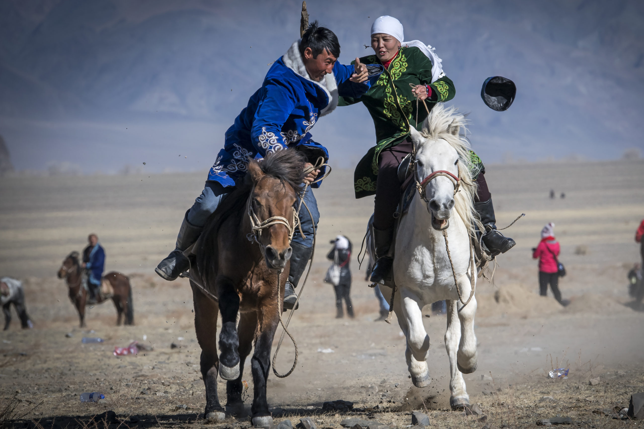 6.7.10.2018. Olgyi; Festival des aigles en Mongolie. Des couples se livrent  la cavalcade de couple. La femme cravachant le mari pour faire fuir son cheval. Ce jeux est appele Kyz KuarPhoto Jean-Guy Python